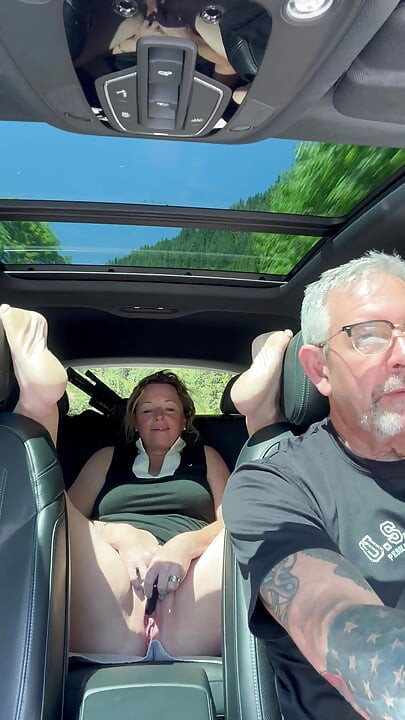 Une femme joue avec sa chatte sur la banquette arrière pendant que son papa conduit, road trip