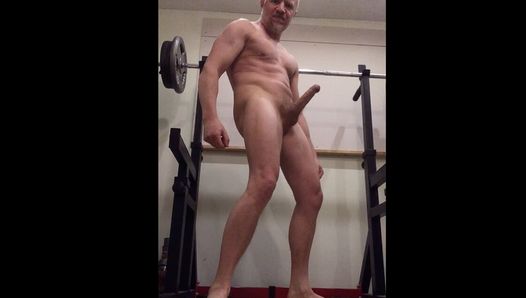 Bodybuilder lekt voorvocht terwijl hij zich buigt met een enorme erectie, voeten toont voor voetaanbidders
