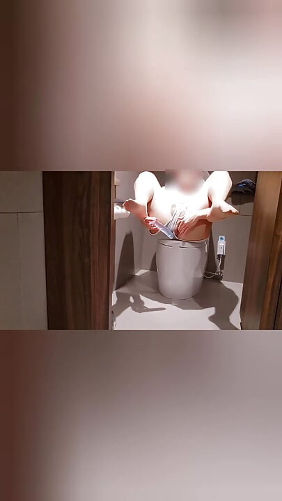 A horny slut enjoys risky pleasure in public men's room, anal masturbates on men's toilets and cums with the door open.