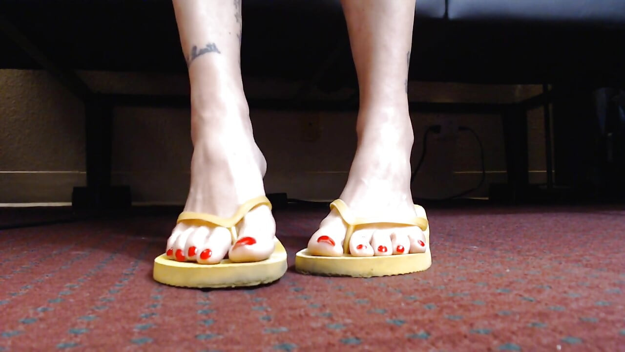 Red toenail wiggling yellow flipflops