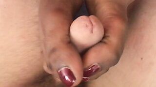 Chica de ébano toca la polla con los pies durante la masturbación