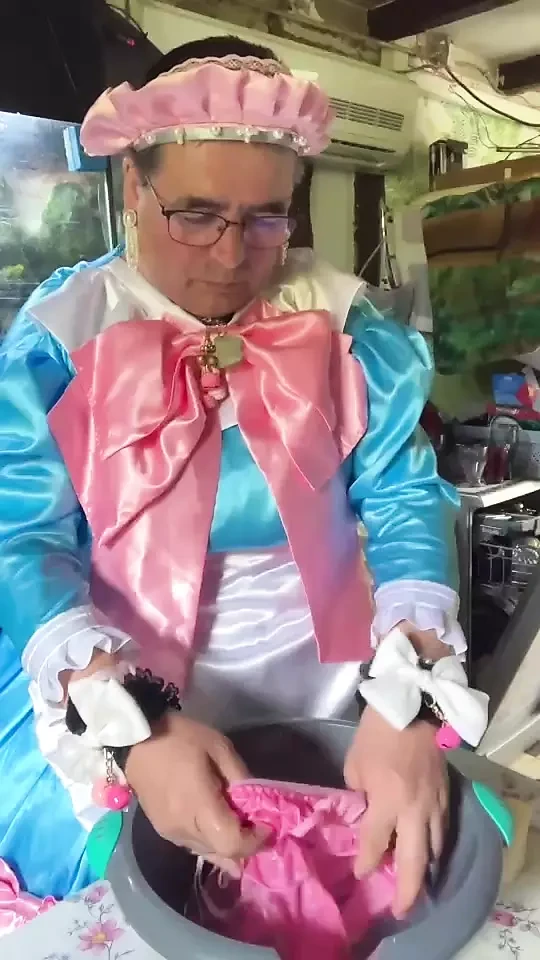 In un vestito da cameriera blu con fiocchi rosa per fare il bucato.
