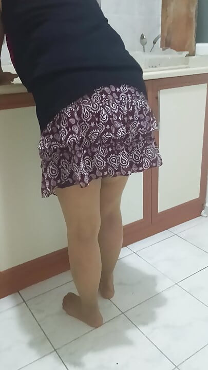 Mujer madura en medias perfectas haciendo las tareas domésticas en la cocina.