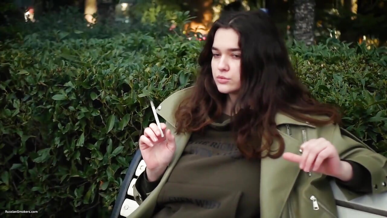 A fiatal barna lány sietség nélkül sétál az Allwhite 120 mm-es cigarettával