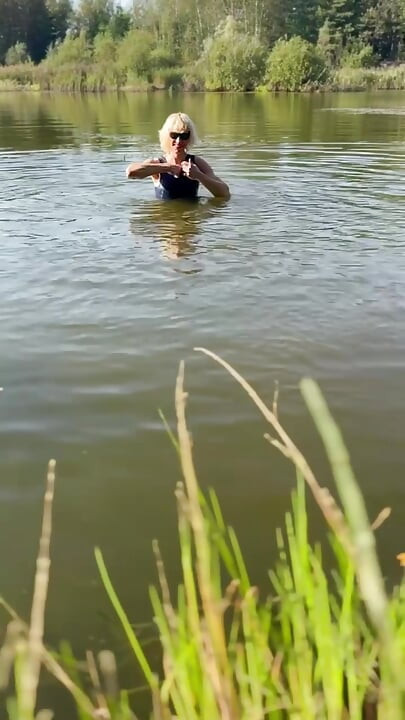 Trans djevojka pliva u jezeru u plavoj sportskoj haljini. Wetllok trans djevojka mokra.