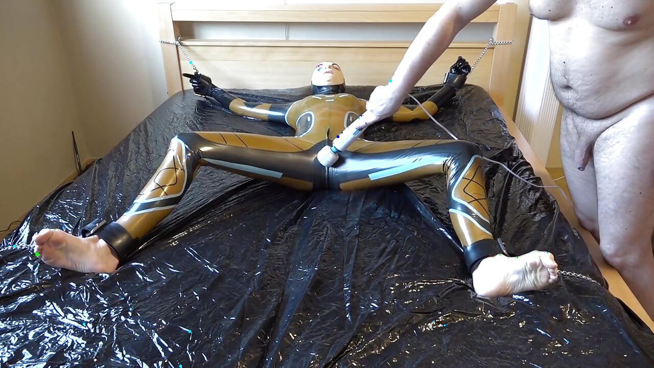Latex Danielle is attached to the bed and masturbated with the massage vibrator