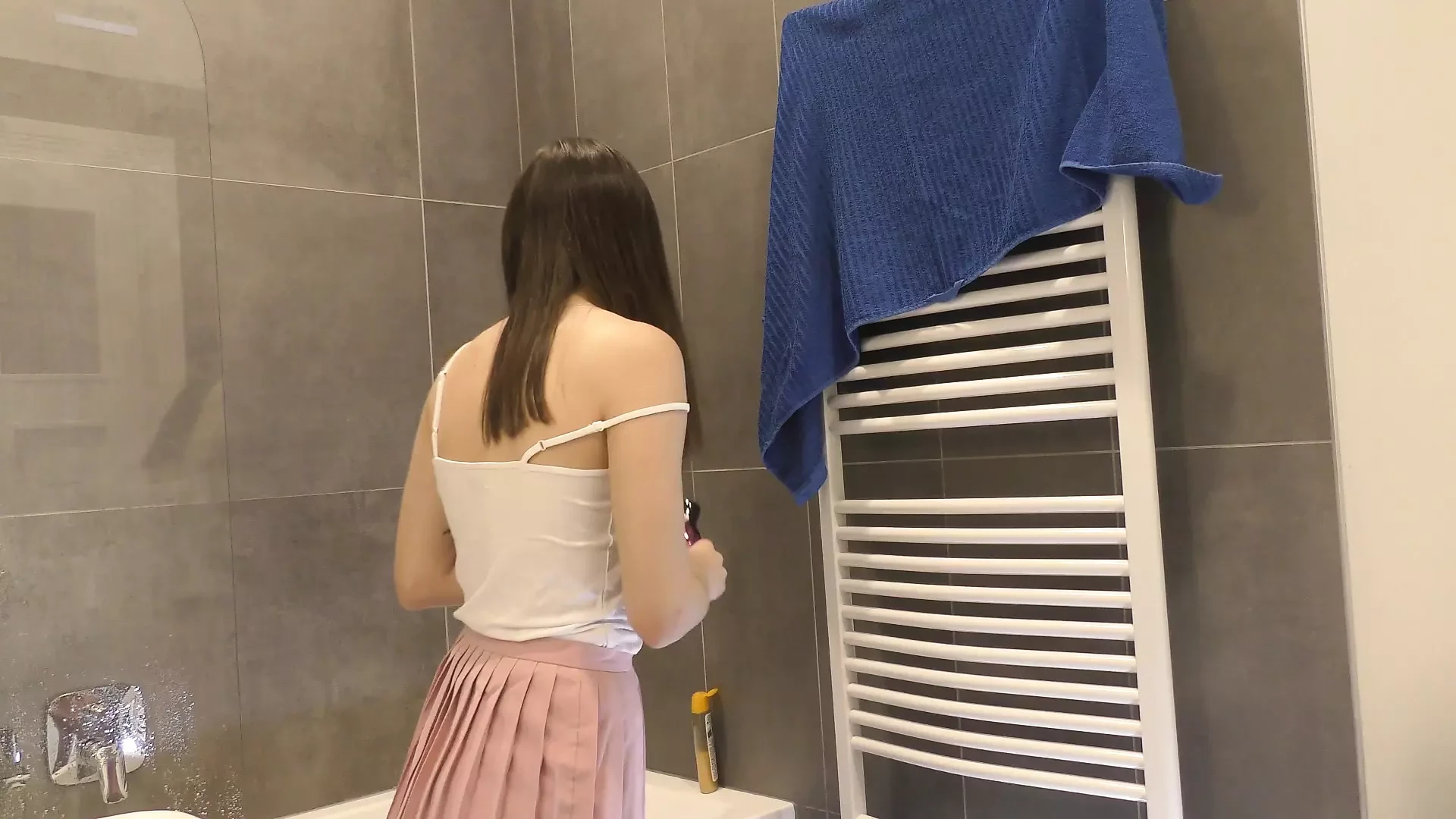 Braless hot brunette skinny and horny babe in a pink mini skirt to show her beautiful ass and legs in the bathroom