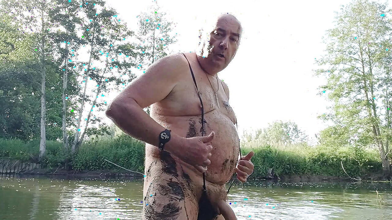 O papai gordo e mustachioed está se divertindo no riacho, se masturbando sem vergonha com lama