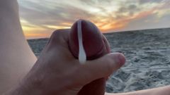 Na zewnątrz masturbacja podnosząca z publicznej plaży o zachodzie słońca