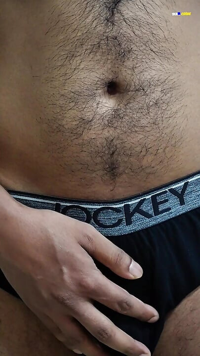 Young man wearing black underwear is dancing cock while holding his groin area.
