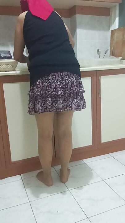 Mature woman in sheer stockings doing housework in the kitchen.