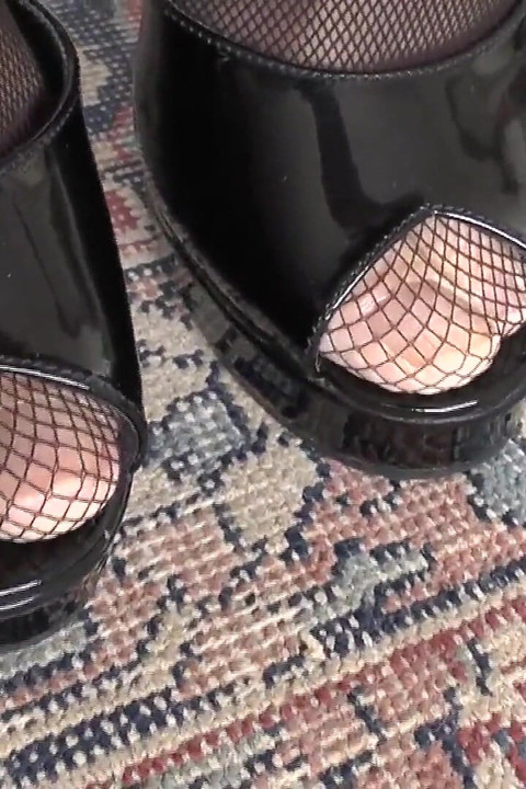 Une déesse des talons hauts exhibe ses mules en cuir noir breveté