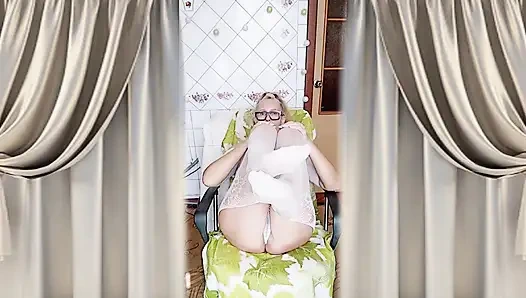 Cheerful housewife Lukerya flirts in an open, transparent white jumpsuit in the kitchen.