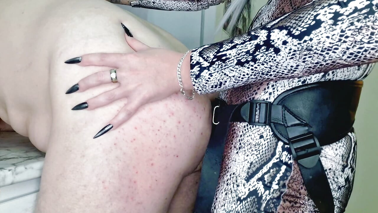 Κοντινό πλάνο πρωκτικού σεξ με στραπόν. Η Dominatrix γαντζώνεται στον κώλο της σκλάβας με τα νύχια της και γαμάει τον κώλο