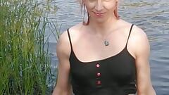 Transgirl zwemt in kleren in het meer en draagt ze allemaal zwart: panty, rok en topje. Wetlook in meer.