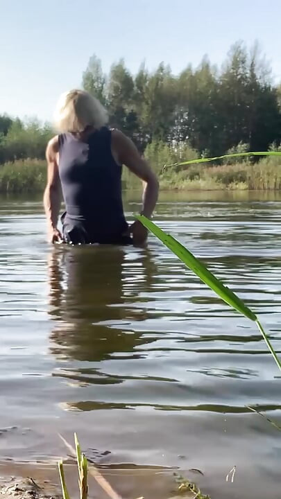 Trans djevojka pliva u jezeru u plavoj sportskoj haljini. Wetllok trans djevojka mokra.