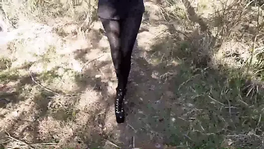Walking wearing a black dress, pantyhose and heels