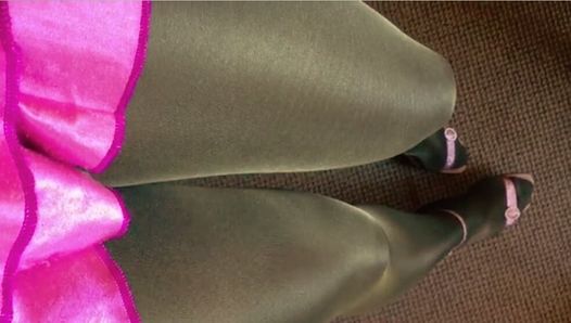 Collants bronzés et noirs, jambes en satin rose, minijupe rose et sandales roses à talons.