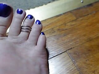 Elle trémoie les orteils avec un anneau des orteils et des ongles violets