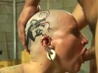 Troia tatuata con piercing alla testa calva inchiodata