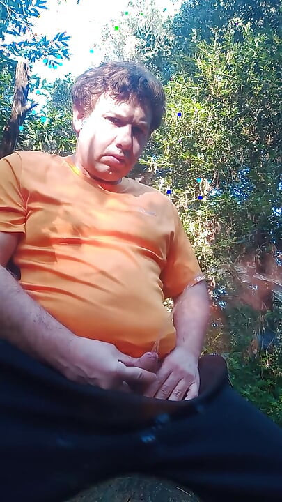 Boy in the woods sitting on a tree trunk pees and then jerks off with saliva coming from his mouth at the end