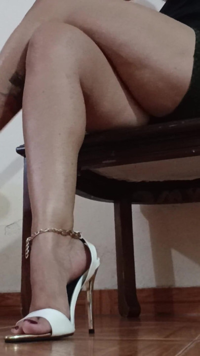 Her Long Legs Are Crossed, and Her High Heels Dangle From Her Feet as She Sips a Delicious Cup of Coffee