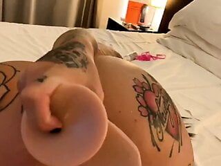 Une petite amie tatouée baise un gode dans le cul dans une chambre d'hôtel