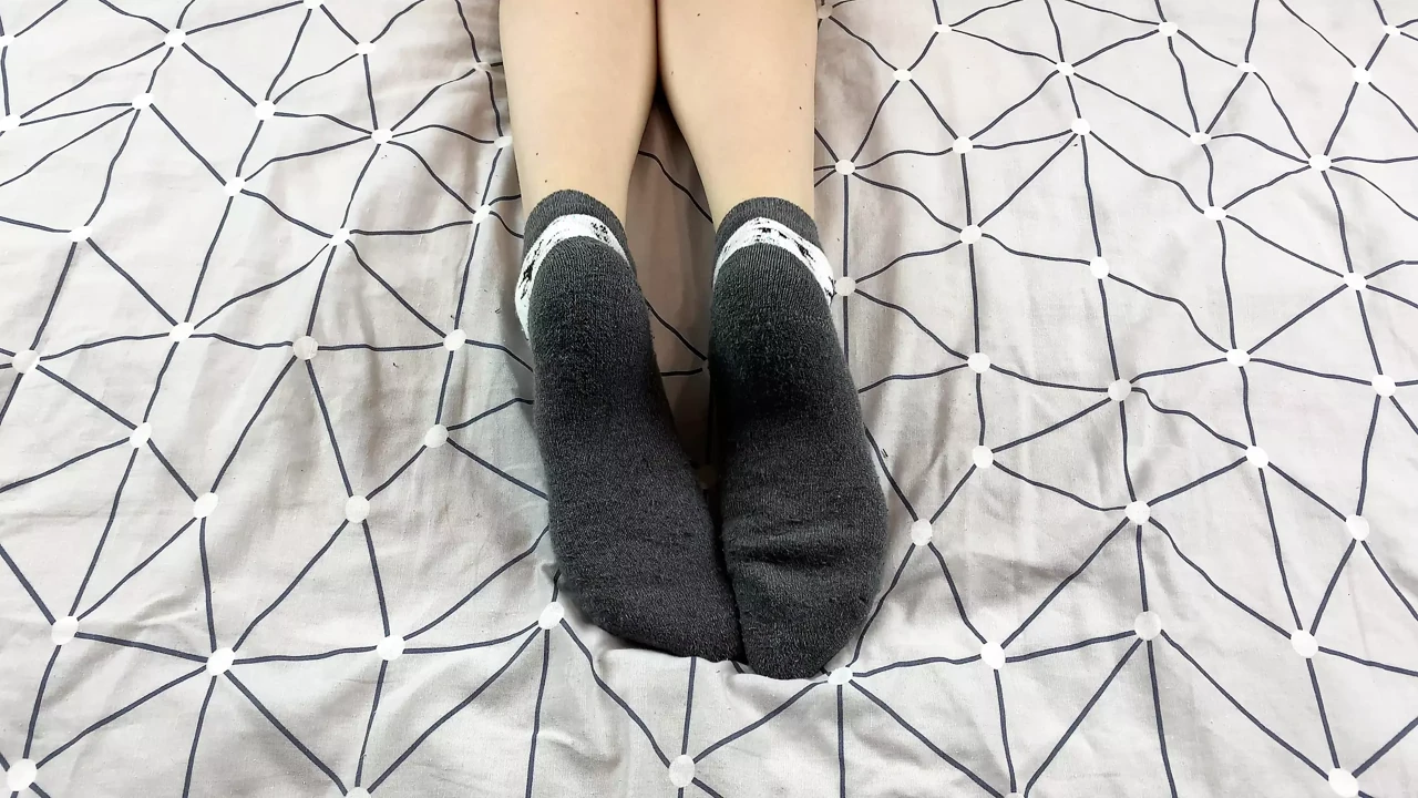 Girl with long legs caresses her feet in gray New Year socks with deer