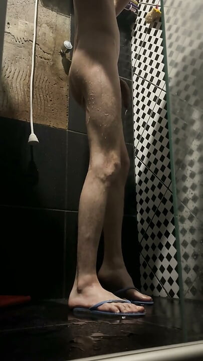 Flaco twink jugando con un juguete en la ducha