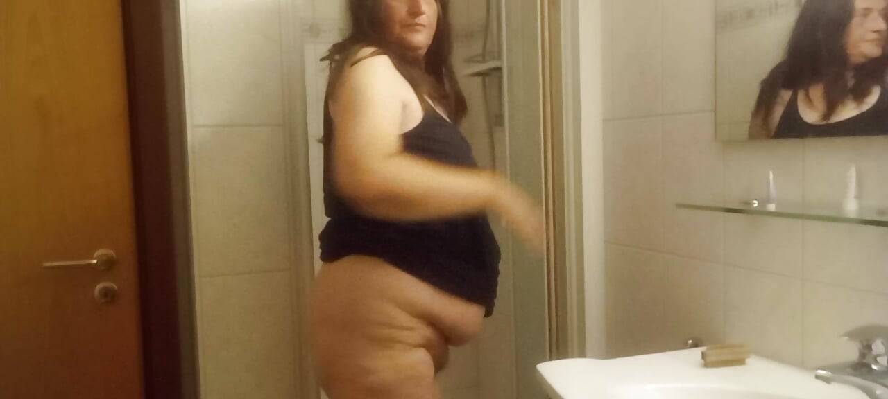Femme mature et ronde sous la douche — son gros ventre est bien visible
