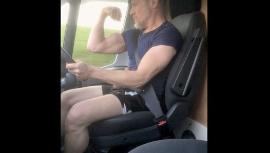 Un papa camionneur musclé se branle et fléchit ses muscles tout en conduisant son camion, en s'allumant