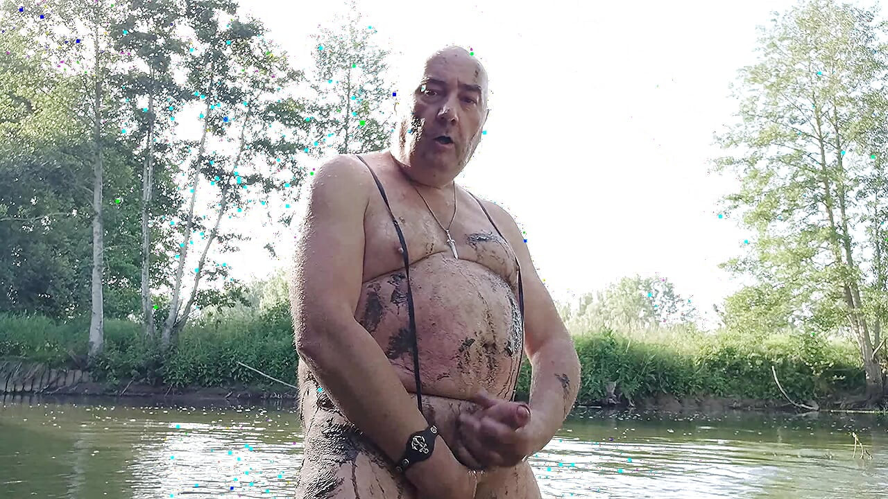 The plump, mustachioed daddy is having a blast in the stream, shamelessly masturbating with mud