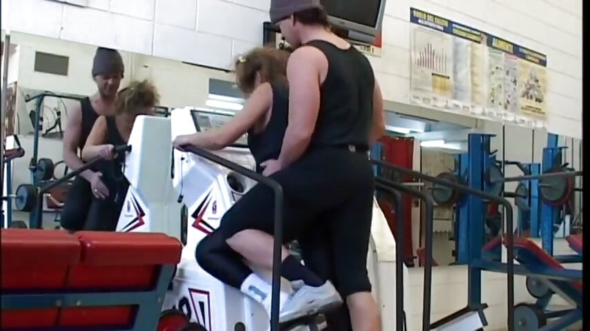Kåt moden kvinde på gymmet prøver at forføre sin træner