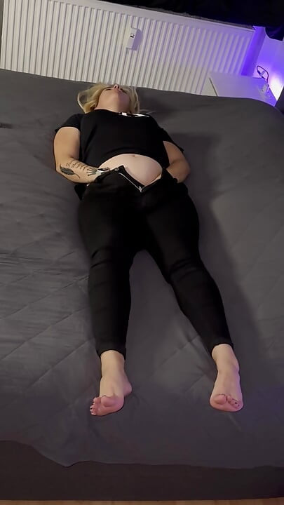 Blonde lady in black gets orgasms while standing behind the camera and watching her