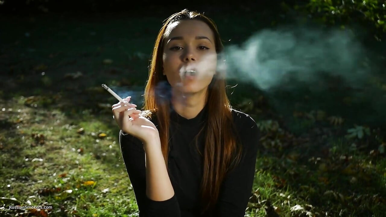 Une beauté russe séduisante fume une cigarette dans la nature