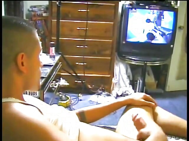 Latino a feleségverőben nézi a tévét, miközben rángatja a húsát