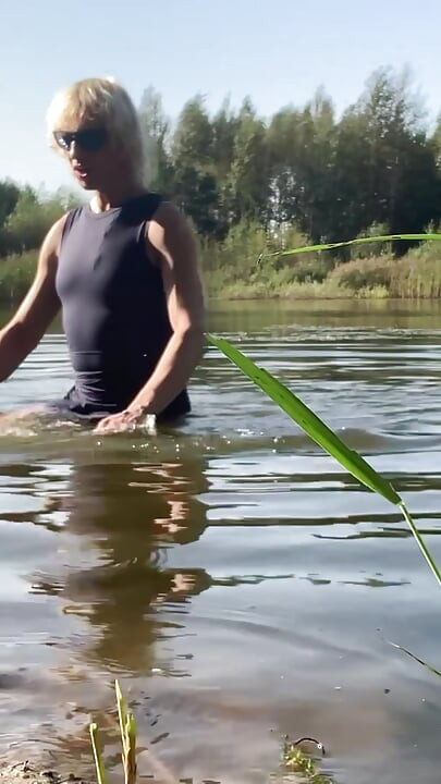 Trans djevojka pliva u jezeru u plavoj sportskoj haljini. Wetllok trans djevojka mokra.