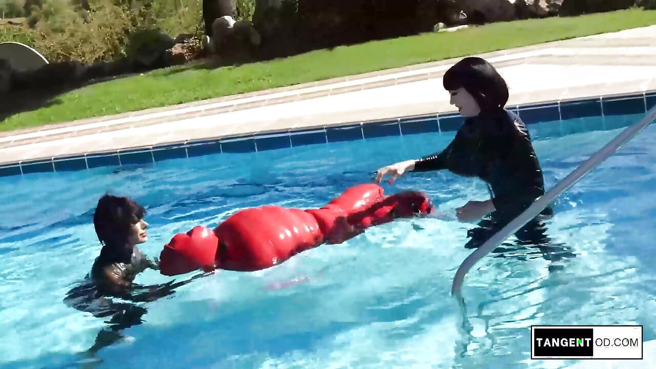 TANGENTOD Women in Black Catsuits Float Red Latex Encased Figure on Inflatable Rubber Pool Toy