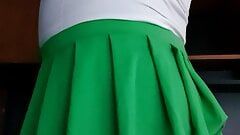 Colegiala sexy en mini falda verde y bragas de satén rosa
