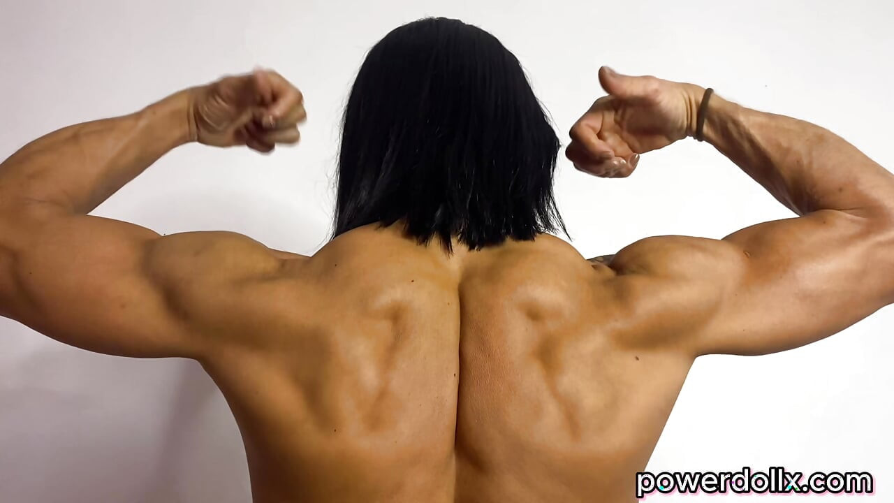 Modelo fitness feminina flexiona enormes bíceps e músculos das costas