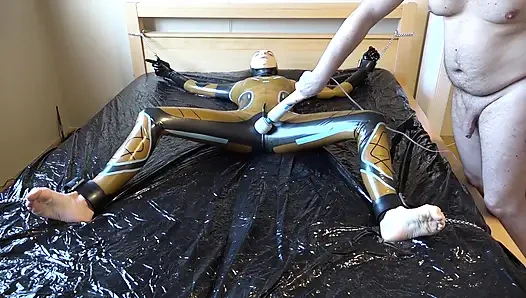 Latex Danielle wird am Bett befestigt und mit der massage mit dem vibrator masturbiert