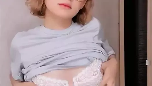 Une fille blanche sexy à lunettes filme un strip-tease très sensuel en vidéo