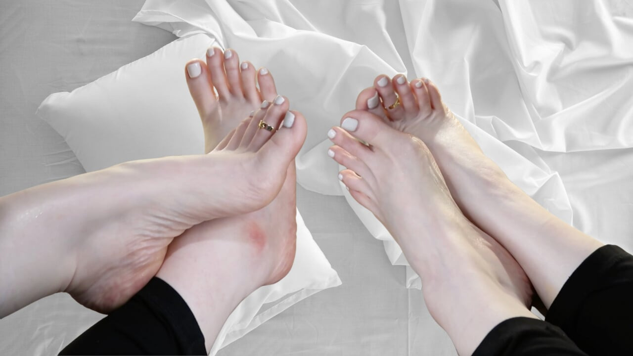 लंबी टांगों और सफेद नेल पॉलिश के साथ सुंदर पैर