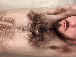 Oskuren vit kille som tvättar sig och visar upp sin mycket håriga bleka kropp i badkaret