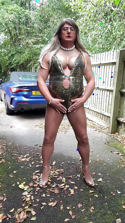 Seksi transvestit kellycd2022 u zlatnom kupaćem kostimu i štiklama čisti lišće