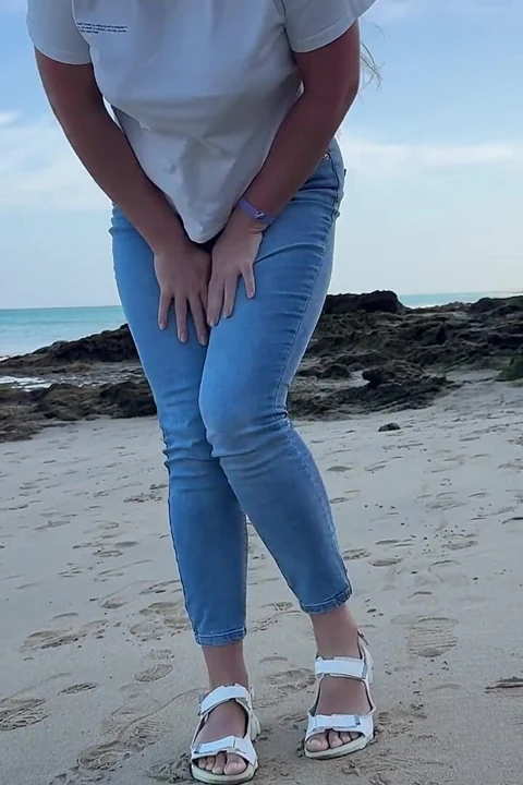 在海滩上穿着紧身牛仔裤撒尿