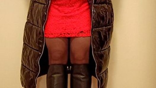 Travesti transexual en abrigo de látex y vestido rojo masturbarse.