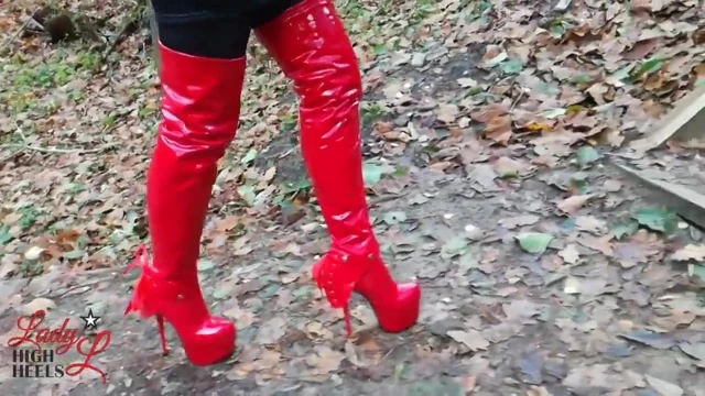 Lady L sexy walking with extreme red boots in forest.