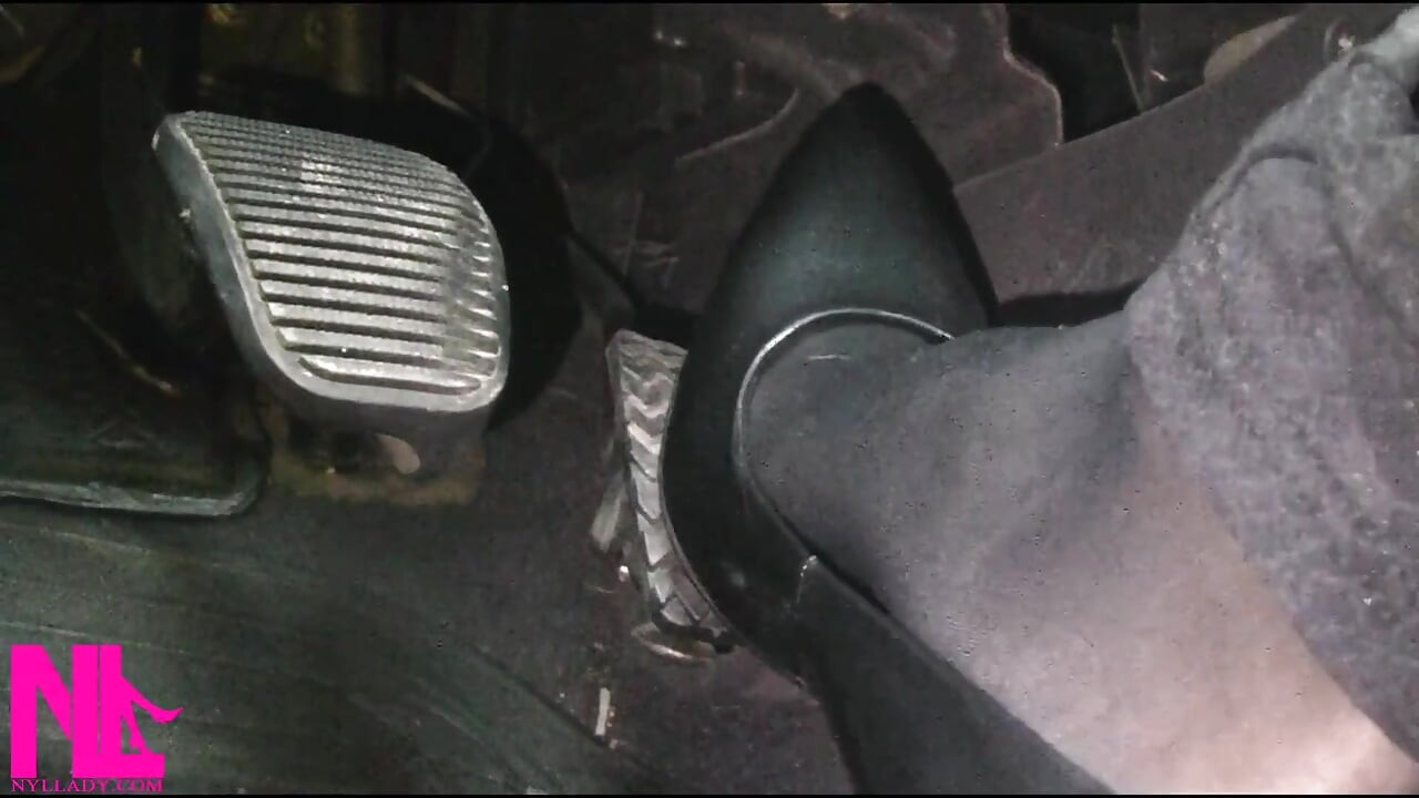 Siyah külotlu çorap ve gri yüksek topuklu ayakkabılarla canlanıp araba sürüyor