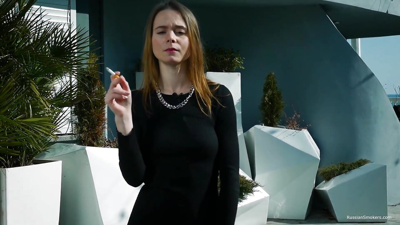 Fată tânără rusoaică care fumează o țigară lângă mal